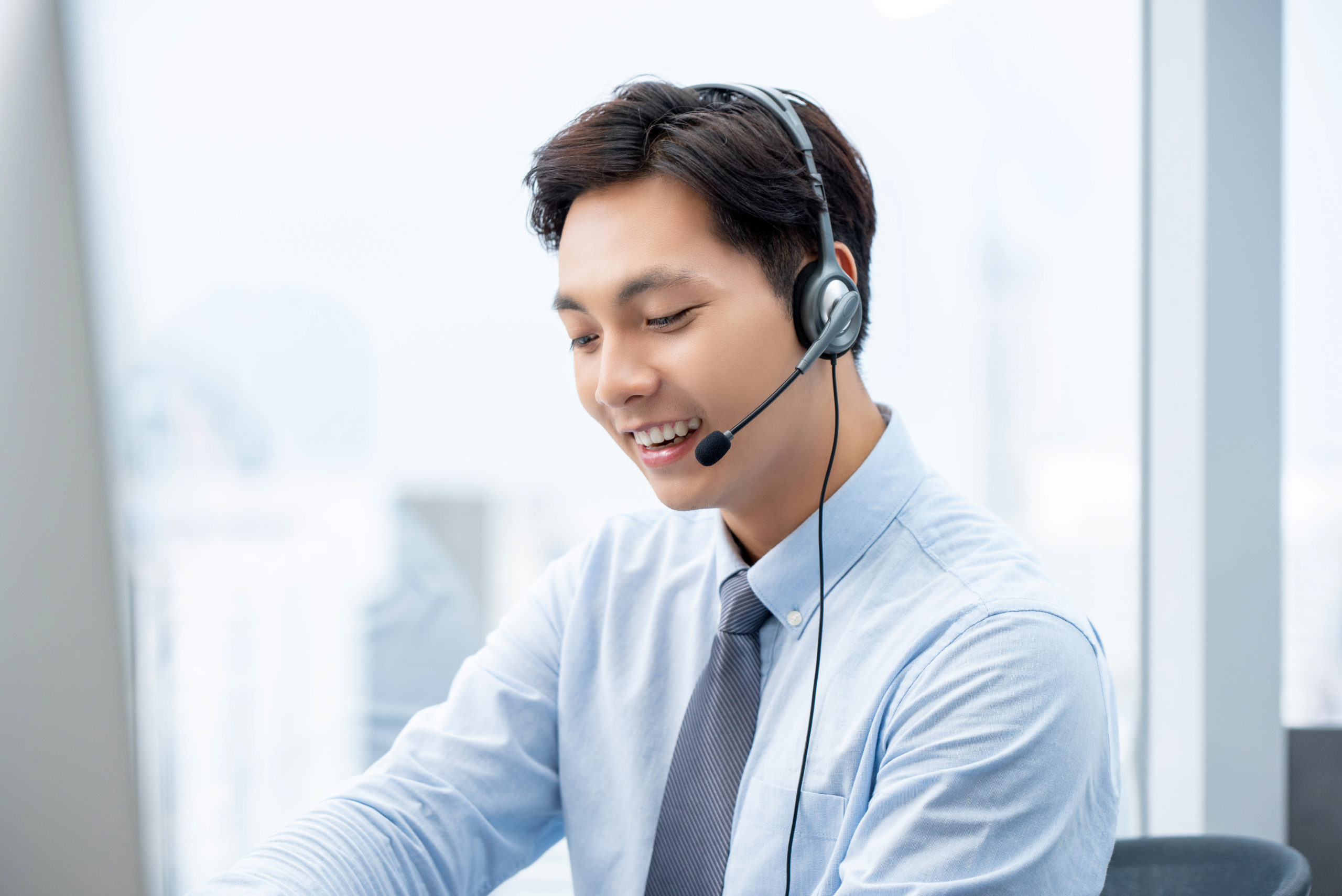 Smiling handsome Asian man working in call center office as a customer service operator